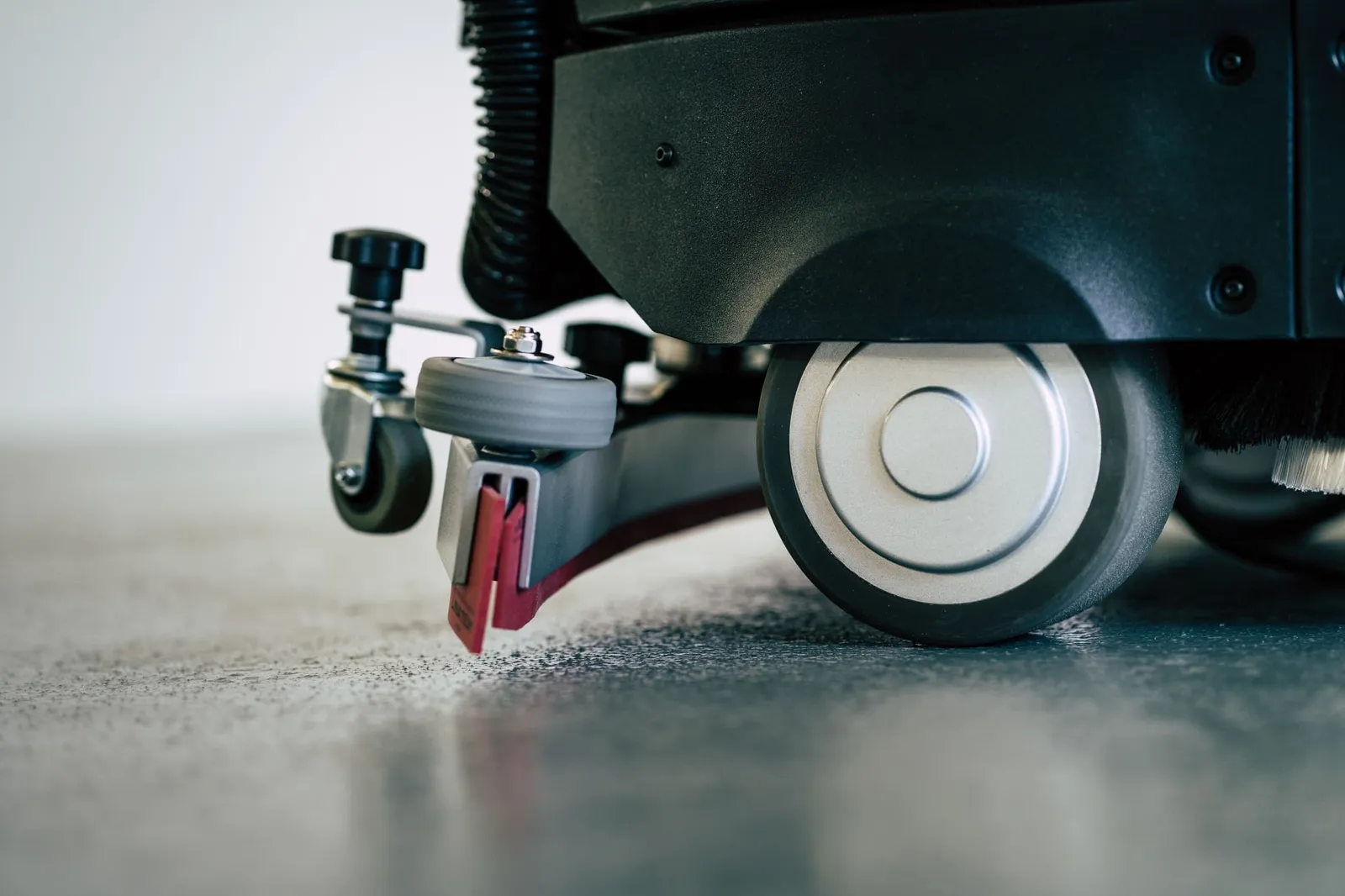 The robot's squeegee and wheel on a wet floor